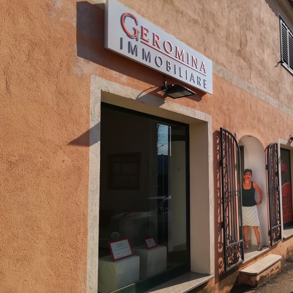 la vetrina e l'insegna di Geromina Immobiliare vicino al lungomare di Cannigione